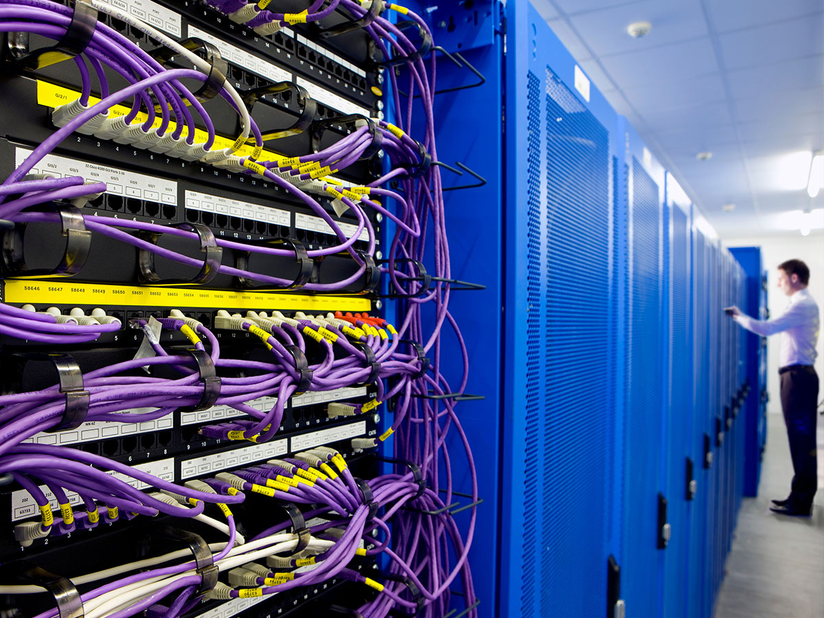 Serverraum mit blauen Racks und Patchpanels — 24/7-Kühlung schützt Hardware
